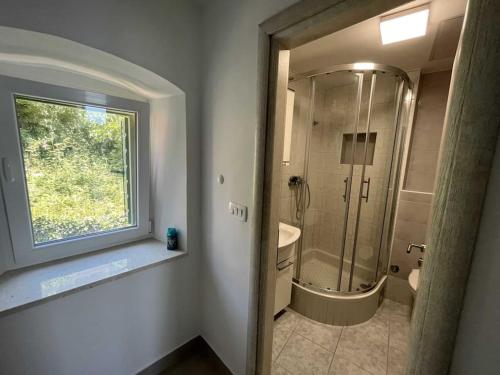 a bathroom with a shower and a toilet and a window at Holiday Home Aria in Podgora