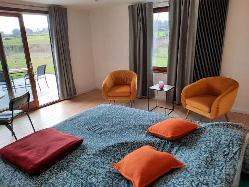 Schlafzimmer mit einem Bett mit orangefarbenen Kissen und Stühlen in der Unterkunft Le Grand Ravel in Weismes