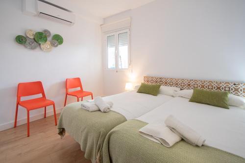 um quarto branco com uma cama grande e 2 cadeiras em Apartamento Malibu Cadiz playa em Cádiz