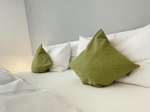 een bed met witte kussens en groene kussens erop bij Ferienwohnung Antonia am Staufenpark in Oberstaufen