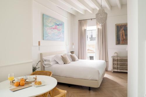 um quarto branco com uma cama e uma mesa em Mylu Suites by Puerta Catedral em Sevilha