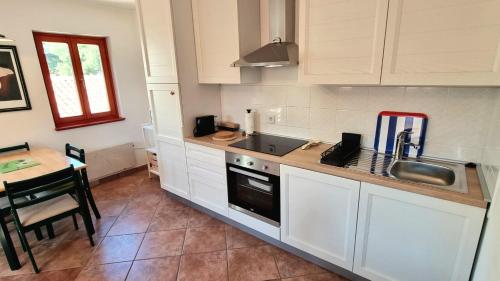 a kitchen with white cabinets and a sink and a table at Old Harbour in Novigrad Istria