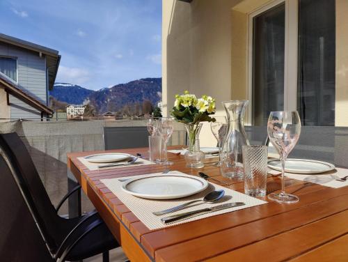 a wooden table with plates and wine glasses on a balcony at Hubel Apartment 14 in Wilderswil