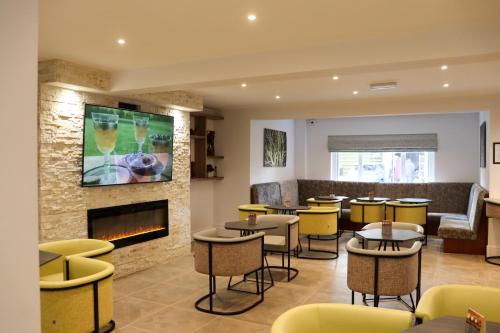 un restaurante con mesas y sillas y una chimenea en Best Western Premier Heronston Hotel & Spa, en Bridgend