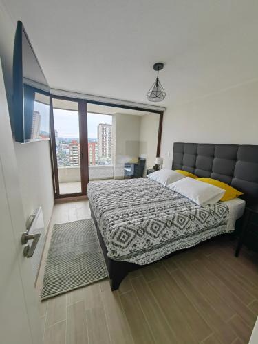 um quarto com uma cama grande e uma janela grande em Departamento céntrico en Temuco con estacionamiento em Temuco