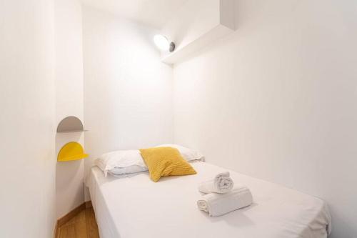 ein weißes Schlafzimmer mit einem weißen Bett und einem gelben Kissen in der Unterkunft Lavie Maison large comfy flat in Bordeaux