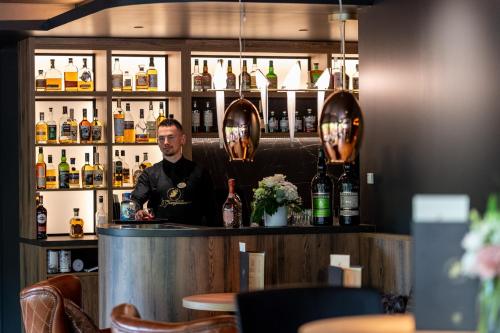 a man standing behind a bar in a restaurant at LA CHENEAUDIÈRE - Hôtel Spa - Relais & Châteaux - Restaurant étoilé in Colroy-la-Roche