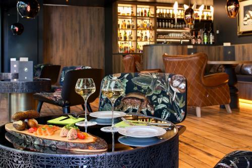 a table with glasses of wine and food on it at LA CHENEAUDIÈRE - Hôtel Spa - Relais & Châteaux - Restaurant étoilé in Colroy-la-Roche
