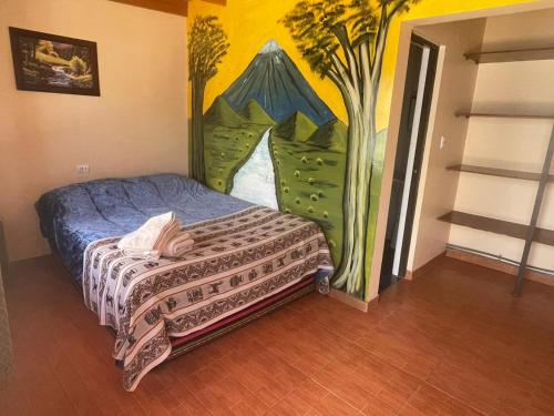 1 dormitorio con 1 cama con una pintura en la pared en Hostal El Amigo Lucho, en San Pedro de Atacama