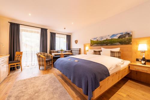 a bedroom with a large bed and a desk and a table at Hotel Rubihaus in Oberstdorf