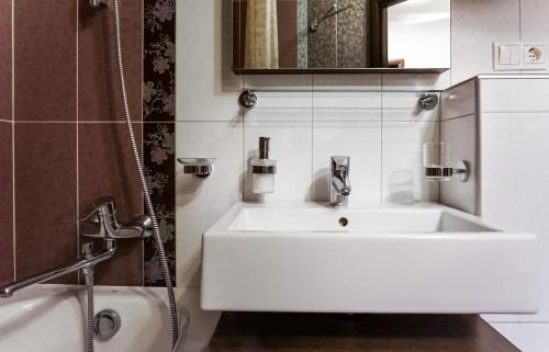 a bathroom with a white sink and a shower at Doba In Ua Peremoga Apartments in Dnipro