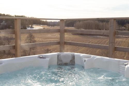 a hot tub on a deck with a fence at Bergs Gård & Hållsvikens Gård in Västerljung