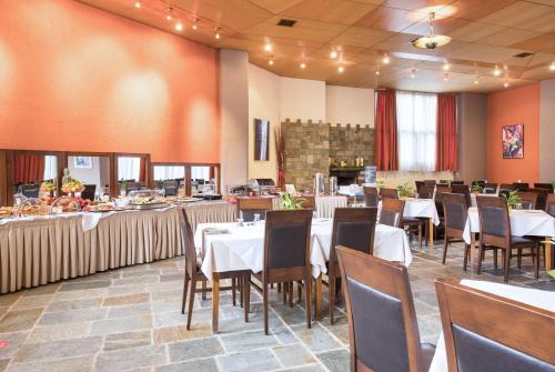 una sala da pranzo con tavoli e sedie bianchi di Arahova Inn Hotel ad Aráchova