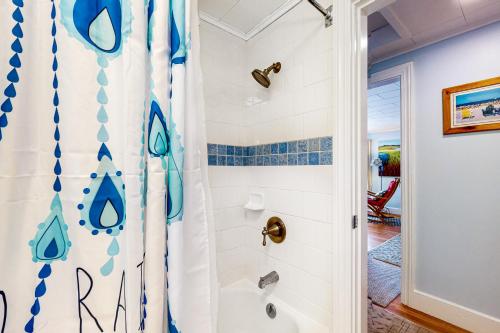 a bathroom with a shower with blue and white tiles at Pineapple Cottage By The Sea in Ogunquit