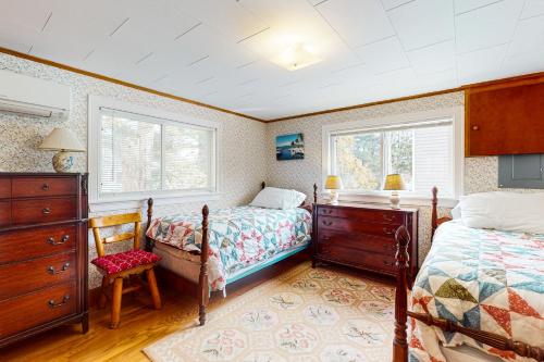 a bedroom with two beds and a dresser and two windows at Pineapple Cottage By The Sea in Ogunquit