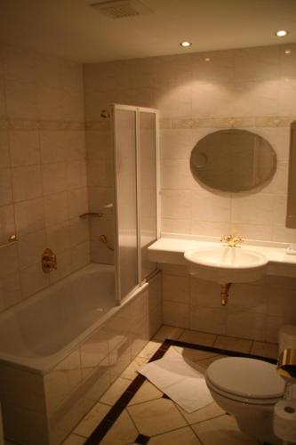 a bathroom with a tub and a sink and a toilet at Hotel garni SEESCHLÖSSCHEN in Kolpinsee