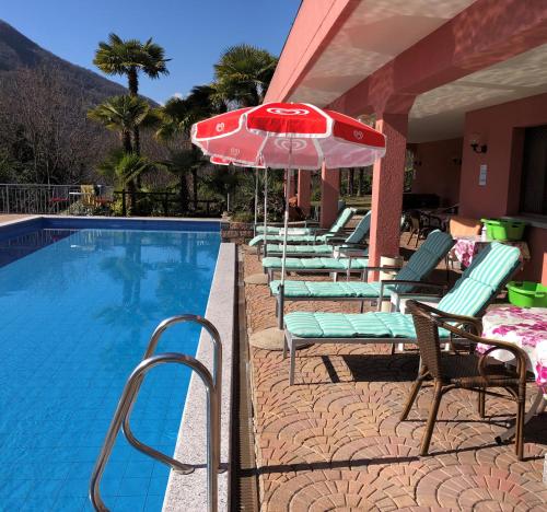 a row of chairs and an umbrella next to a swimming pool at Villa del Sole Garni in Ponte Tresa