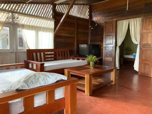1 dormitorio con 2 camas, mesa y TV en Villa Tsara - Vacances de rêve à la mer en Nosy Be