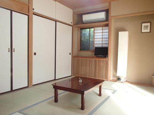 a living room with a table and a tv at B&B Kumakara in Kamakura