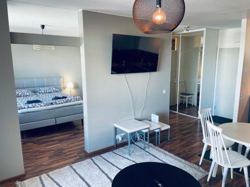 uma sala de estar com uma cama, uma mesa e cadeiras em Tapiola Center Apartment em Espoo