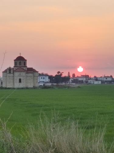 an old building in a field with the sunset in the background at Palm garden paradise in Pervolia