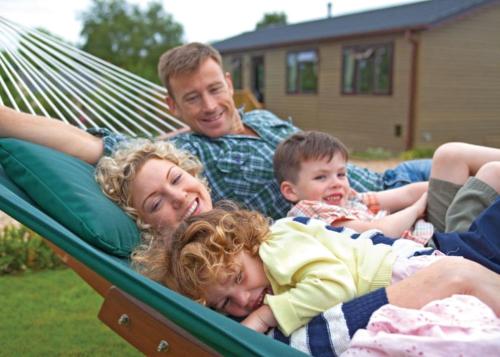 kobieta i dwoje dzieci leżących w hamaku w obiekcie Ashby Woulds Lodges And Spa w mieście Moira