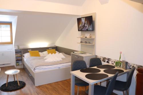 Apartmán Justýna Horní Blatná في هورني بلاتنا: غرفة نوم صغيرة بسرير وطاولة وكراسي