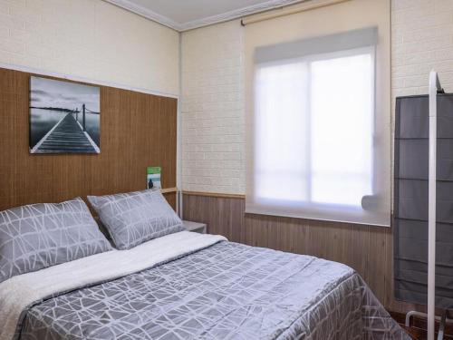 Un dormitorio con una cama grande y una ventana en Casa con piscina a 5 min de la playa, en Burriana