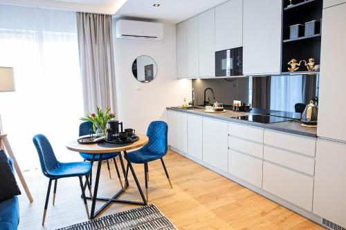 a kitchen with white cabinets and a table and chairs at Apartamenty STUDIO M in Busko-Zdrój