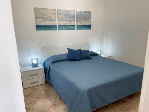 a bedroom with a blue bed and two pictures on the wall at GIOIA'S HOUSE in Custonaci