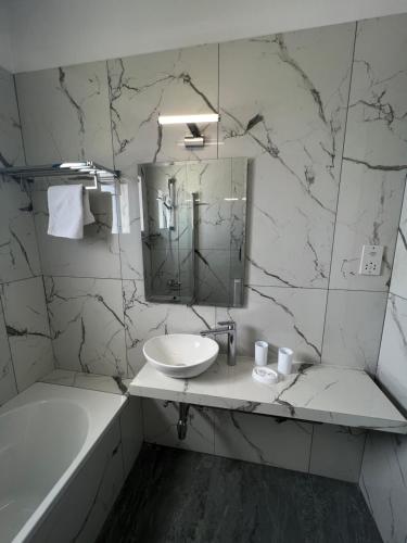 帕福斯的住宿－科法羅尼緹公寓酒店，浴室配有盥洗盆、镜子和浴缸