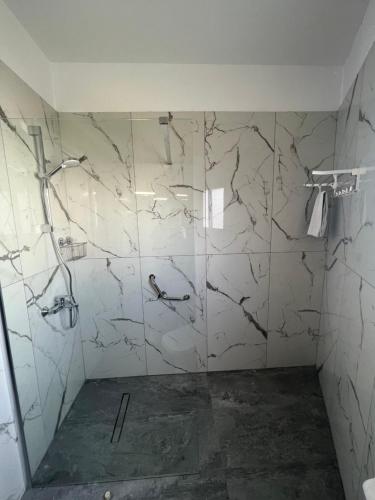 a bathroom with a white marbleiled walls and a shower at Kefalonitis Hotel Apartments in Paphos City