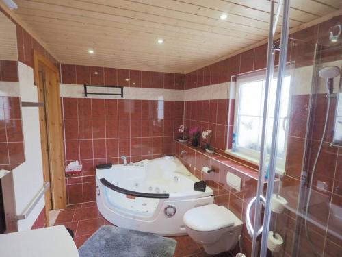 een badkamer met een bad, een toilet en een douche bij Ferienhaus Sissi mit Whirlpool, Sauna u sehr ruhig in Großschönau