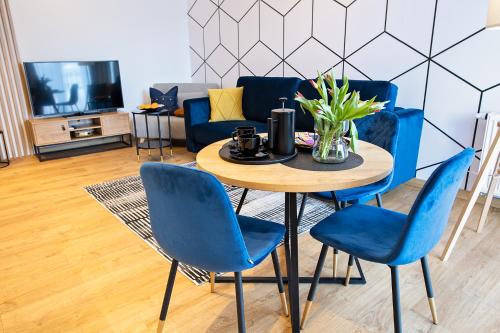 Una sala de estar con una mesa y sillas azules. en Apartamenty STUDIO M, en Busko-Zdrój