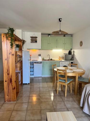 une cuisine avec des armoires vertes, une table et des chaises dans l'établissement AS23037 -P2 avec parking privé à 2 pas de la plage, au Grau-du-Roi