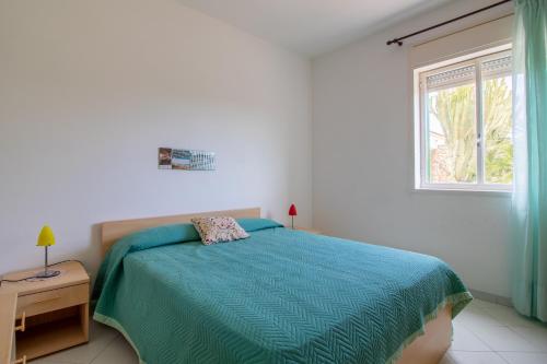 1 dormitorio con 1 cama con edredón azul y ventana en Villetta a due passi dal mare, en Granelli