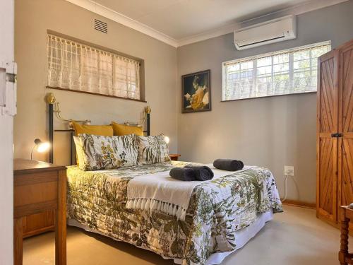 a bedroom with a bed and a dresser and two windows at Farm stay at Rosemary Cottage on Haldon Estate in Bloemfontein