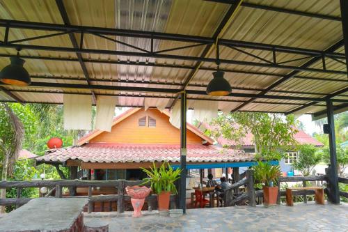 an outdoor patio with a roof with a building at ภูผาฮิลล์ รีสอร์ท in Lan Saka