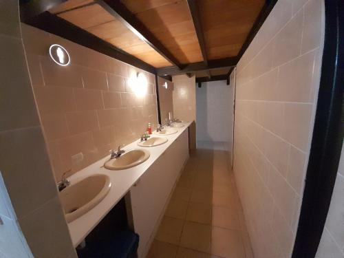 Baño con 3 lavabos y una fila de espejos en Hostal Casa Búho, en Antigua Guatemala