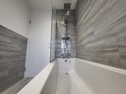 a bathroom with a white tub and a shower at Bright Modern 3 Bedroom Apartment in Sutton