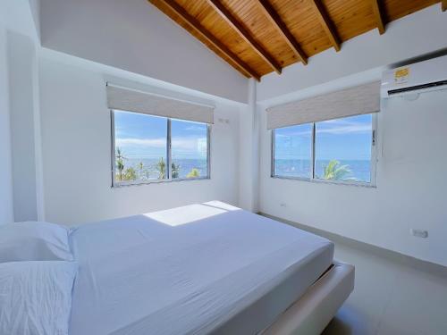 Condominio bahia blanca في كوفيناس: غرفة نوم بيضاء بها نافذتين وسرير