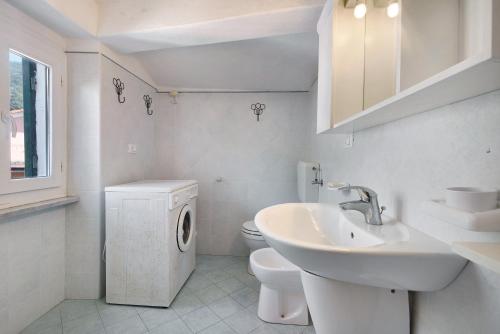 y baño blanco con lavabo y lavadora. en Serra Trilocale, en Bonassola