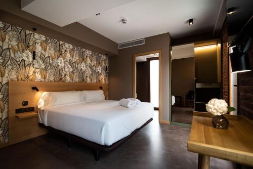 a bedroom with a large white bed and a table at Hotel Atari in San Sebastián