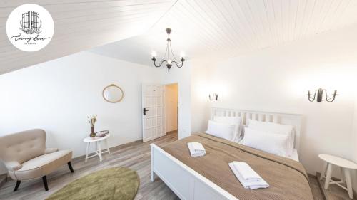 ein weißes Schlafzimmer mit einem großen Bett und einem Stuhl in der Unterkunft Penzión Čarovný dvor 
