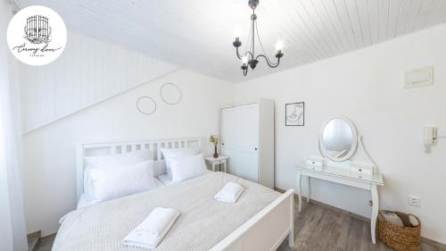 a white bedroom with a bed and a mirror at Penzión Čarovný dvor 