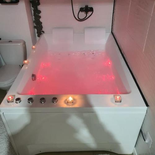 La salle de bains est pourvue d'une baignoire blanche avec des lumières rouges. dans l'établissement studio avec balnéo proche mer, à Moriani-Plage