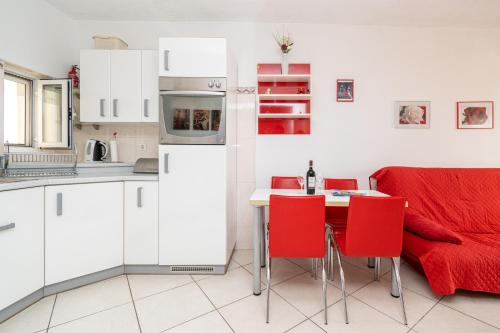 une cuisine avec un canapé rouge et une table avec des chaises rouges dans l'établissement Apartment Bazen, à Zadar