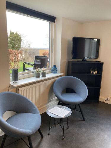 a living room with two chairs and a tv at Guesthouse Dybbøl, Sønderborg in Sønderborg