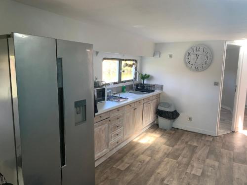 une cuisine avec un évier et une horloge murale dans l'établissement chambres dans peniche un air de vacances, à Toulouse