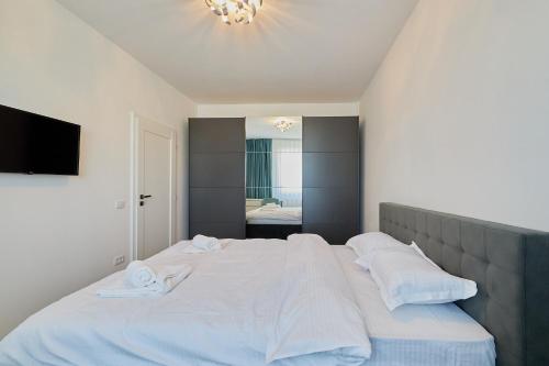 una camera da letto con un grande letto con lenzuola e cuscini bianchi di Alessandro Home 7 Luxury Centru Palas Mall Iași Q Residence a Iaşi